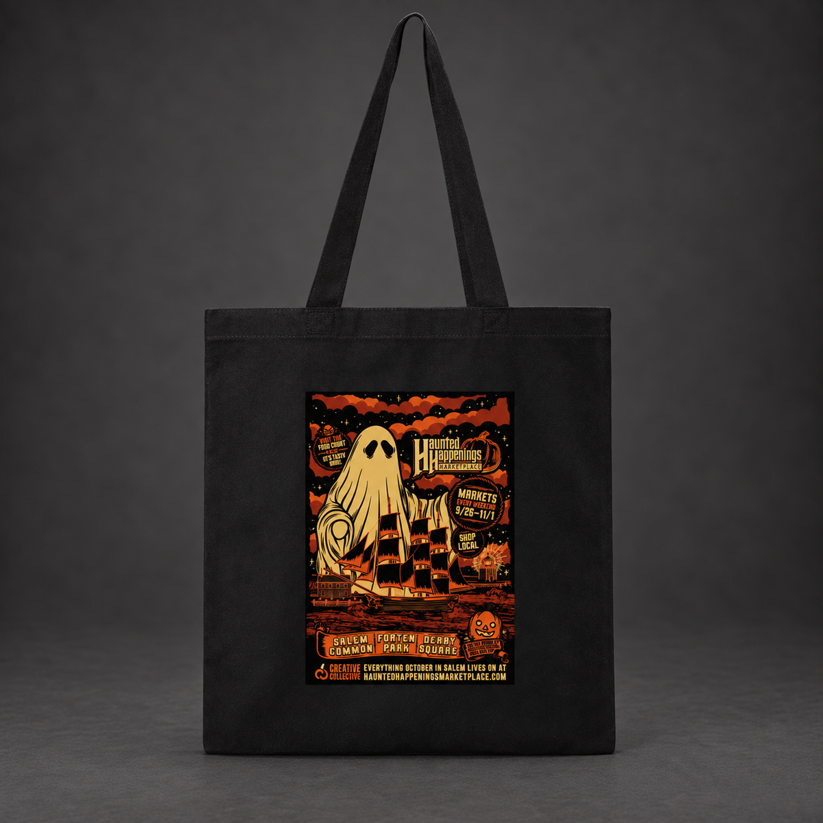 Mockup of a black Kaiju Ghost tote with gold ghost and sailing ship artwork against a charcoal background.