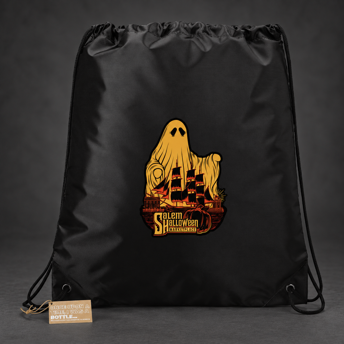 Black Salem Halloween Marketplace drawstring backpack with gold ghost and orange ship artwork on a subtle charcoal background; retouched art proof.