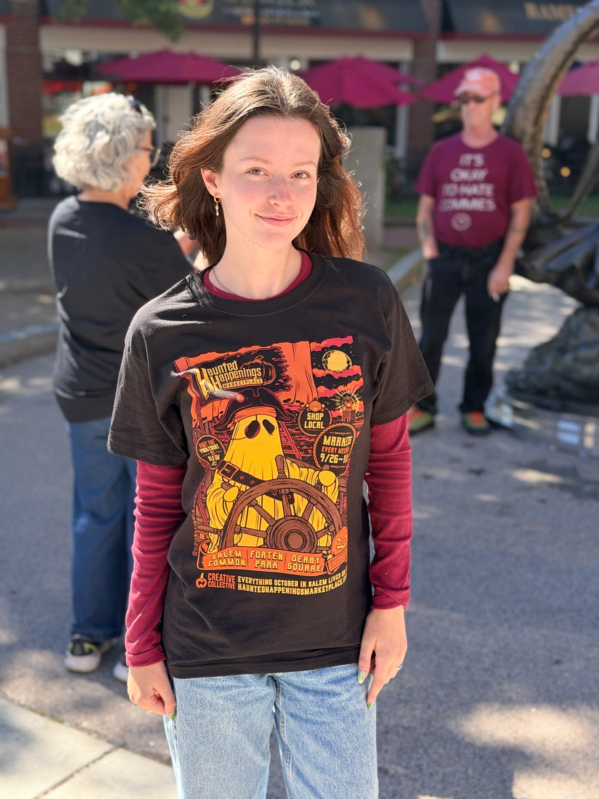 Front view of the 2026 black Pirate Ghost T-shirt with orange and gold ghost-at-the-wheel artwork.